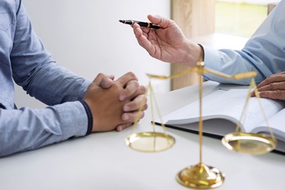 Business lawyer sitting down with a client at a desk while holding a pen