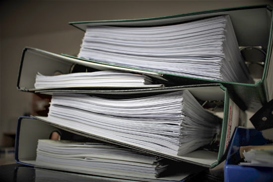 Several binders stacked on top of each other, all full of paper