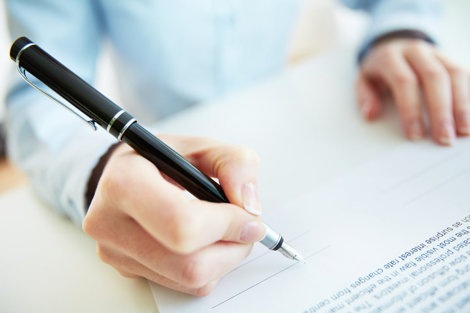 Close up of a man's hand holding a pen, ready to sign a contract